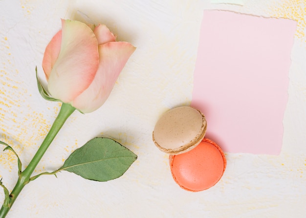 Gratis foto roze bloem met papier en koekjes op tafel