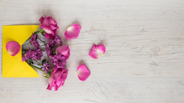 Roze bloemen in envelop op tafel