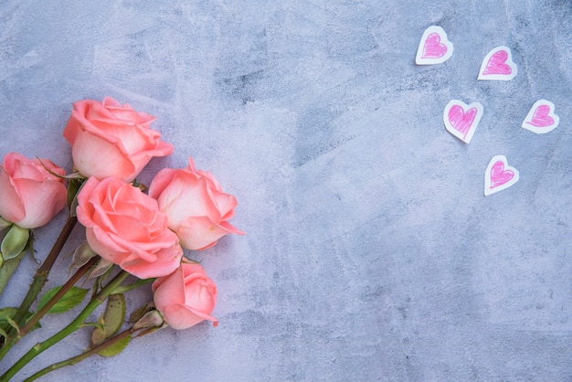 Roze bloemen met papieren harten op tafel