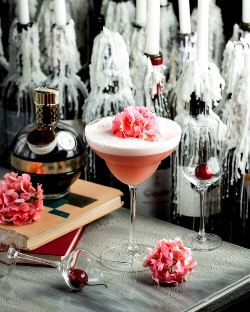 Roze cocktail in glas met lange steel gegarneerd met een bloem