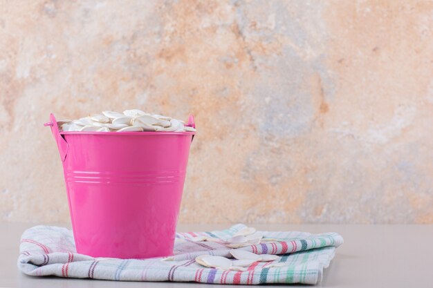 Roze emmer vol biologische pompoenpitten op witte achtergrond. Hoge kwaliteit foto