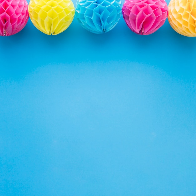 Gratis foto roze en gele honingraat pom-pom papier ballen decoratie op blauwe achtergrond