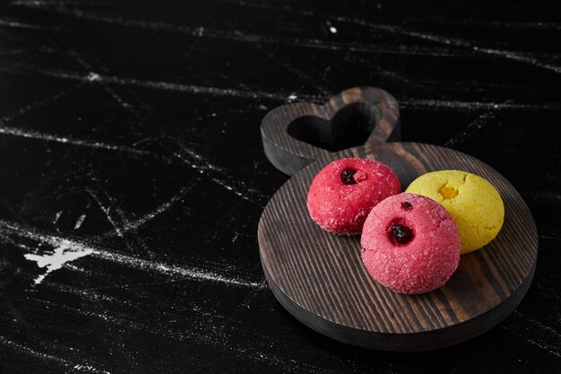 Roze en gele koekjes op een houten bord.