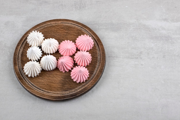 Roze en witte meringue op een bord, op de marmeren tafel.