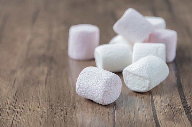 Roze en witte pluizige marshmallows op een houten bord.