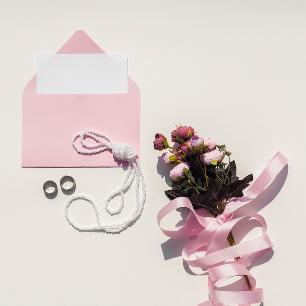Gratis foto roze envelop met bruiloft uitnodiging naast boeket rozen