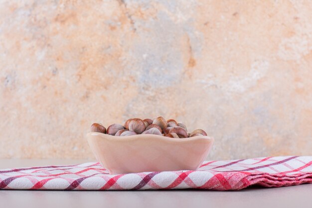 Roze kom gepelde organische hazelnoten die op witte achtergrond worden geplaatst. hoge kwaliteit foto