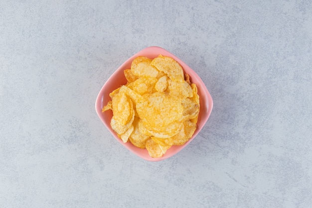 Roze kom heerlijke knapperige chips op stenen achtergrond.