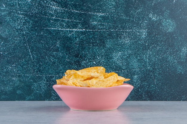 Roze kom heerlijke knapperige chips op stenen achtergrond.