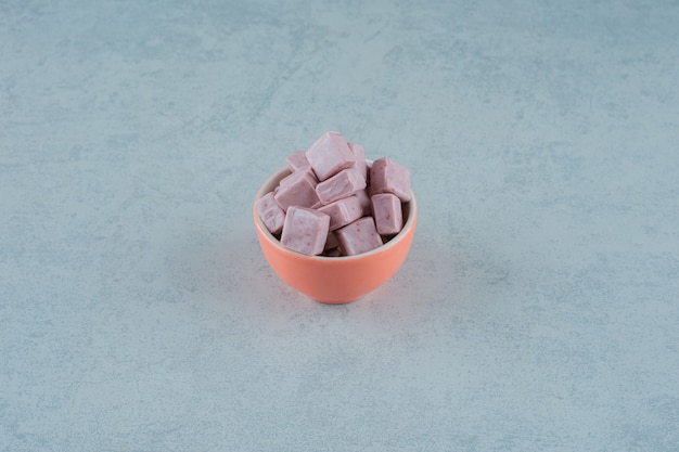 Roze marshmallow-snoepjes in een kom op witte ondergrond