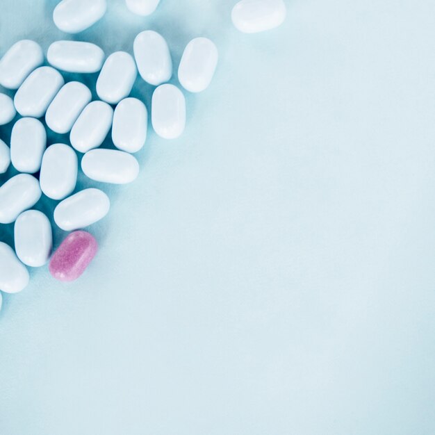 Roze pillen met witte tabletten over de blauwe achtergrond