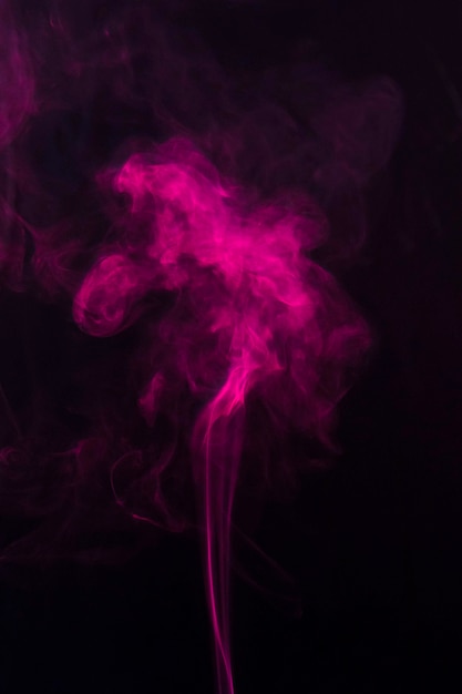 Gratis foto roze rook die zich omhoog over de zwarte achtergrond beweegt