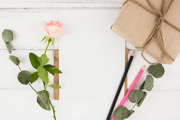 Roze roos; kleurpotlood en gewikkeld geschenkdoos op houten tafel