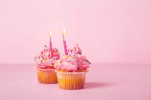 Roze verjaardag cupcake met aangestoken kaarsen