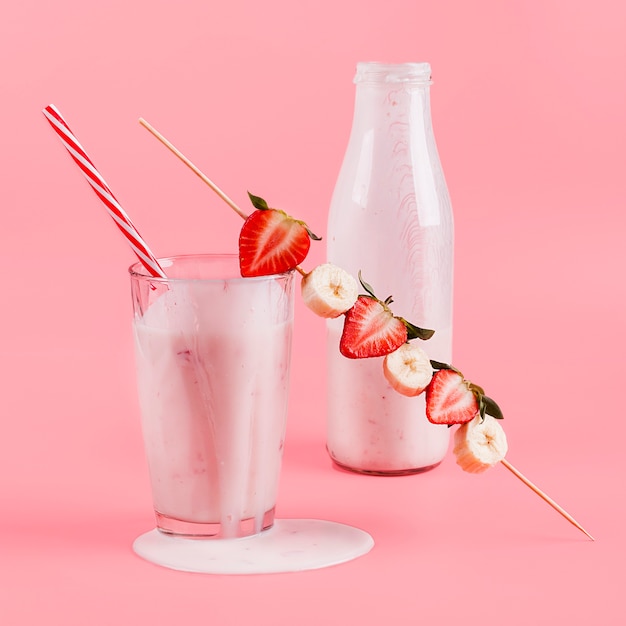 Roze yoghurt in fles en glas met bessen