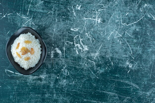 Rozijnen op een kom rijstpudding, op de blauwe achtergrond. Hoge kwaliteit foto