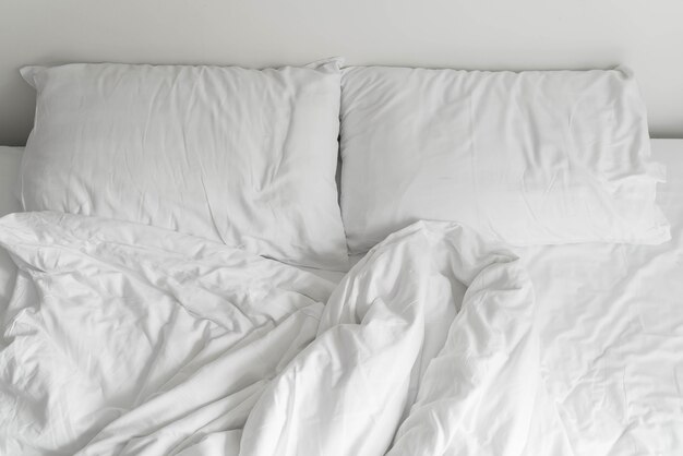 Rumpled bed met witte rommelige kussen decoratie in de slaapkamer