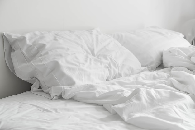 Rumpled bed met witte rommelige kussen decoratie in de slaapkamer