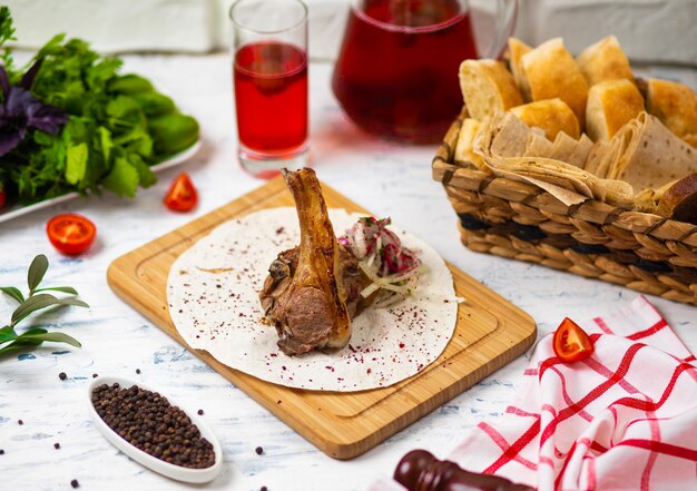 Rundvlees lamskotelet maaltijd in lavash op houten plaat met uiensalade, brood, vegetabels en wijn