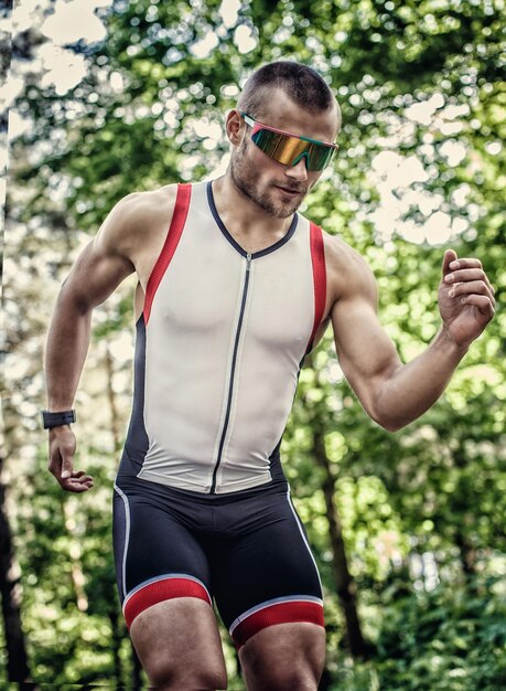 Runner man in sportkleding en zonnebril bereidt zich voor op een snelle start.