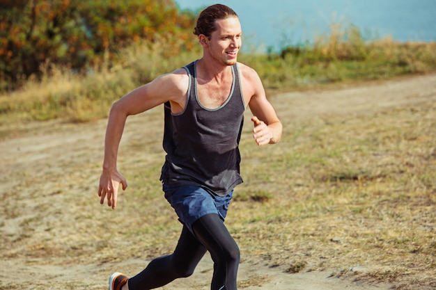 Running sport. Man runner sprinten buiten in de schilderachtige natuur. Fit gespierde mannelijke atleet training parcours uitgevoerd voor marathon run.