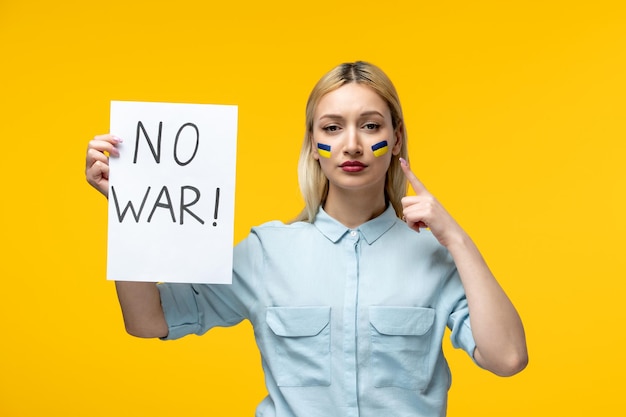 Russische oekraïense conflict schattig meisje gele achtergrond met oekraïense vlag op wangen geen oorlogsteken Premium Foto