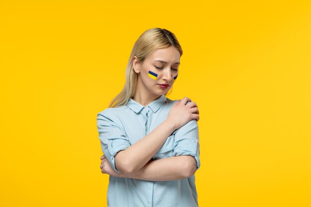 Russische Oekraïense conflict schattig meisje gele achtergrond met Oekraïense vlag op wangen omarmen
