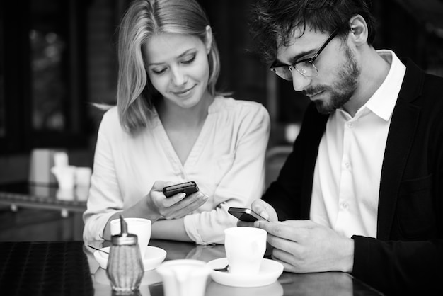 Gratis foto rustgevend paar verbonden met smartphone in coffeeshop