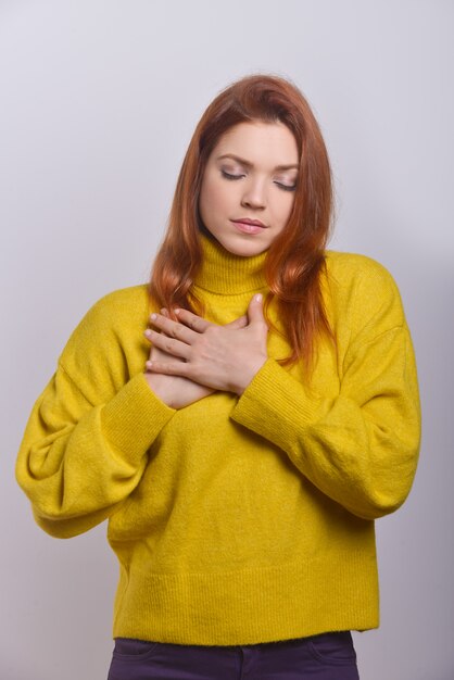 Rustige jonge vrouw met de handen op de borst