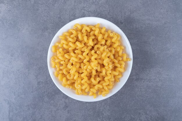 Ruwe elleboog macaroni op witte plaat.