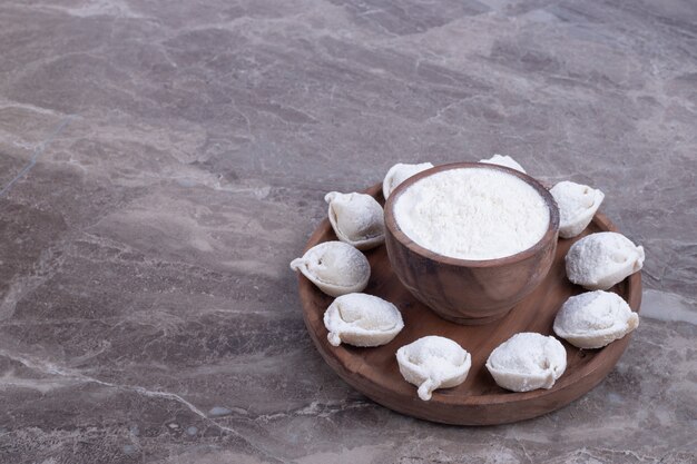 Ruwe knoedels op een houten bord.