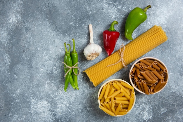 Ruwe spaghetti met groenten op een houten bord.