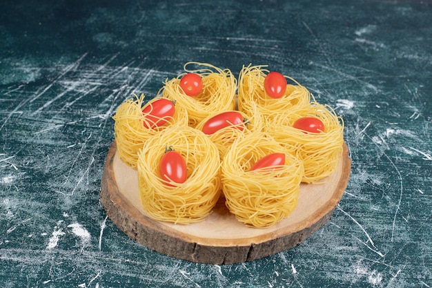 Ruwe spaghetti nesten met tomaten op een houten bord. Hoge kwaliteit foto