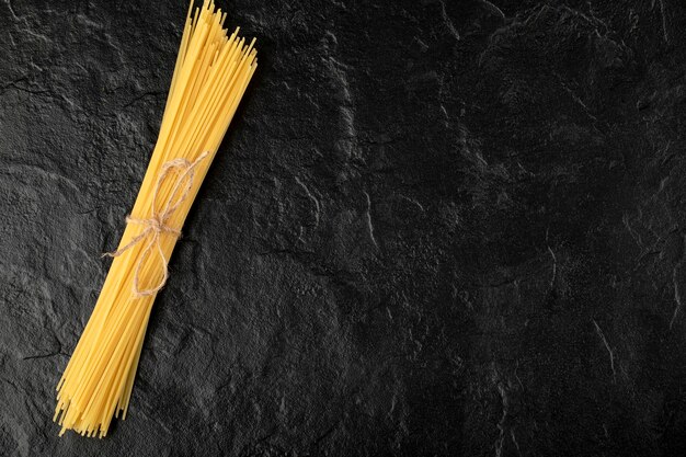 Ruwe spaghetti vastgebonden met touw op zwarte ondergrond