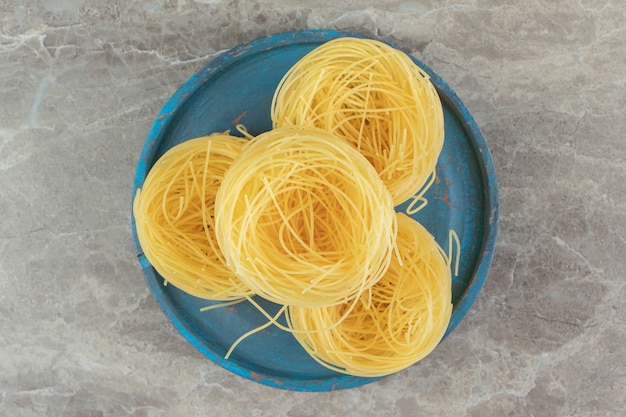 Ruwe spaghettinesten op blauw bord