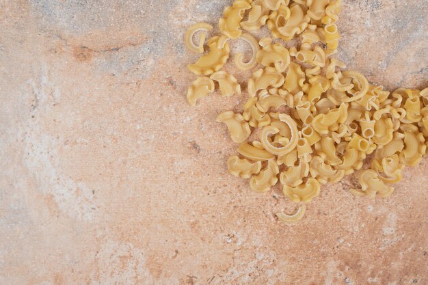 Ruwe spiraalvormige macaroni op marmeren ruimte.