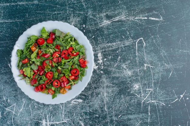 Salade met gehakte groene kruiden en rode chilipepers.