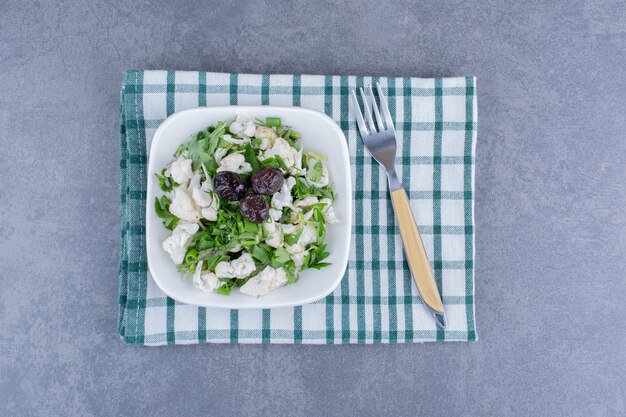 Salade met groene kruiden, bloemkool en zwarte olijven