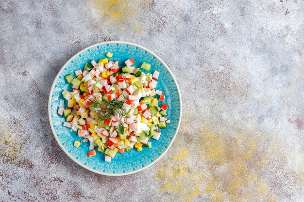 Salade met krabsticks, eieren, maïs en komkommer.