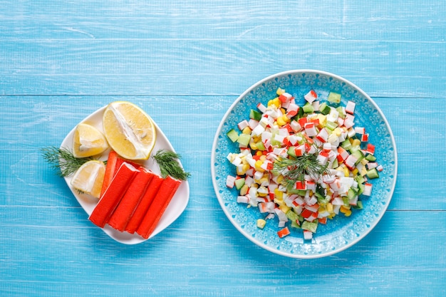 Salade met krabsticks, eieren, maïs en komkommer.