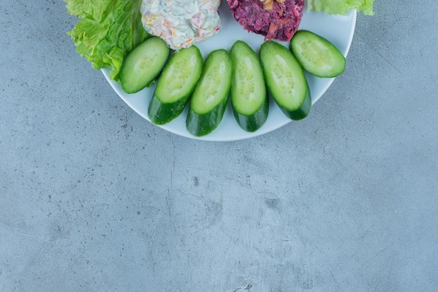 Salade porties versierd met plakjes komkommer en slablaadjes op marmeren oppervlak