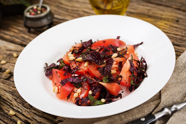 Salade van tomaten met een violet basilicum en pijnboompitten. Veganistisch eten. Italiaanse maaltijd.