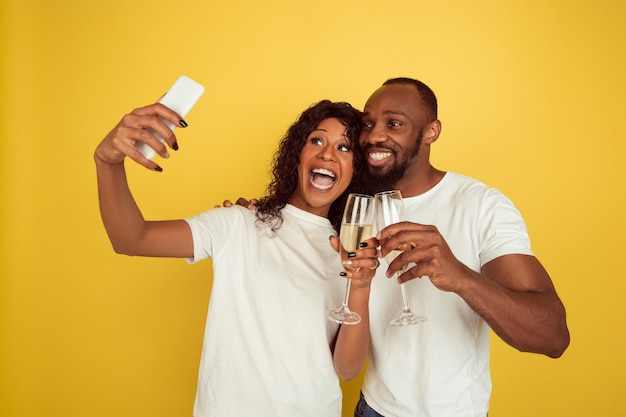 Samen selfie maken. gelukkig Afrikaans-Amerikaans paar geïsoleerd op gele muur. Concept van menselijke emoties, gezichtsuitdrukking, liefde, relaties, romantische vakanties.