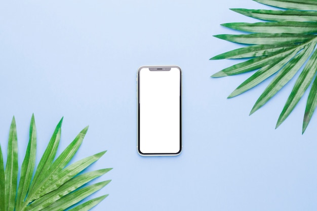 Samenstelling van smartphone met wit scherm en plant bladeren