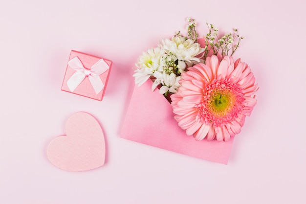 Samenstelling van verse bloemen in envelop dichtbij huidig en sierhart