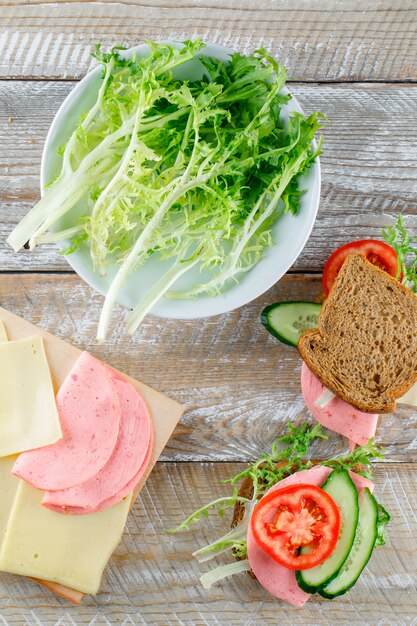 Sandwich met brood, kaas, tomaat, komkommer, worst, Groenen op houten en snijplank, bovenaanzicht.