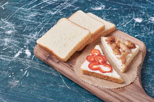 Sandwichbrood op houten bord op blauwe lijst.