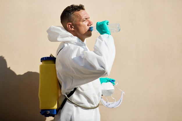 Sanitaire medewerker in hazmat-pak met een waterpauze buiten