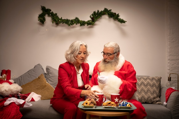 Gratis foto santa claus en vrouw die koekjes hebben