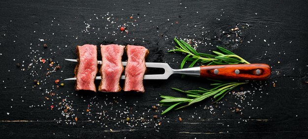 Sappige steak op de vork met kruiden en specerijen. bovenaanzicht. vrije ruimte voor uw tekst.